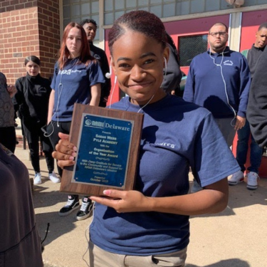  Photo of NAMI recipient holding award for Sarah Pyle Academy